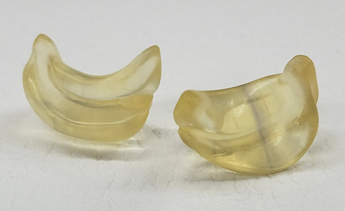 Two mini fluorite banana carvings on a white background