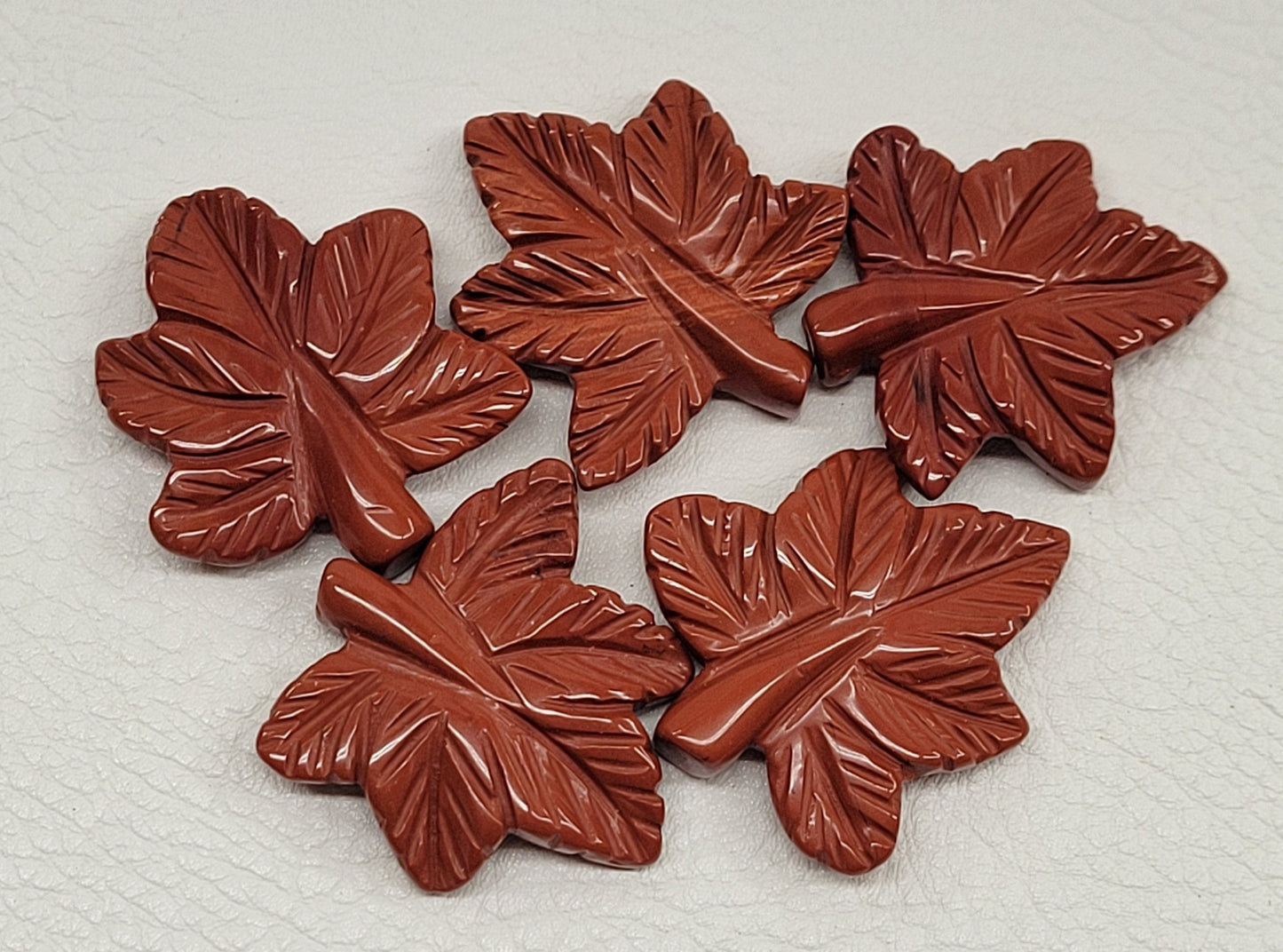 Collection of Red Jasper Maple leaf shaped carvings on a white background