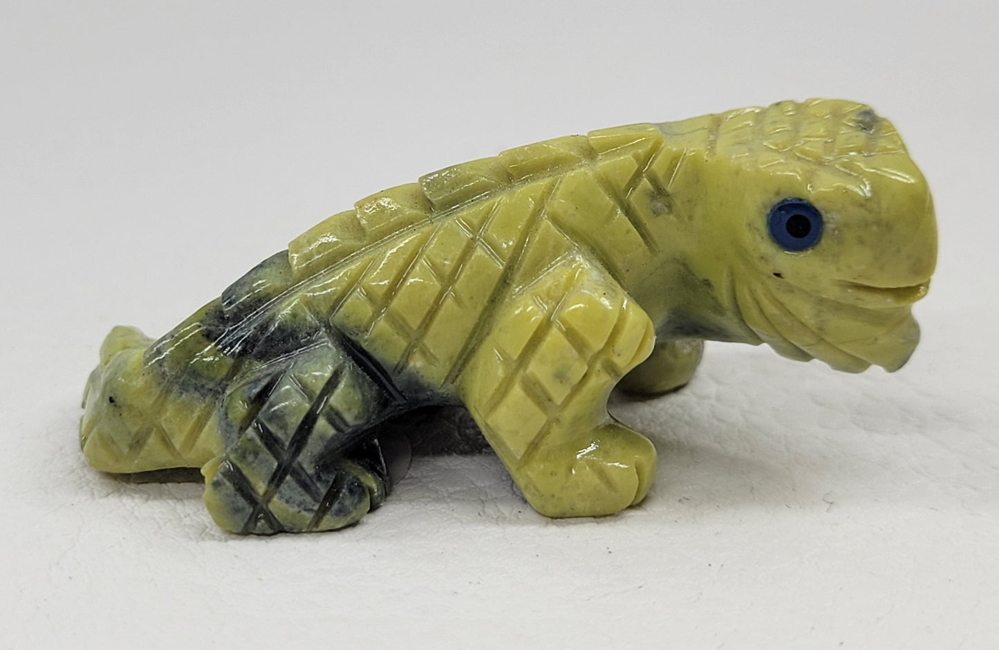 A hand-carved jade lizard with green and beige patterns, each lizard is approximately 2 inches in size.