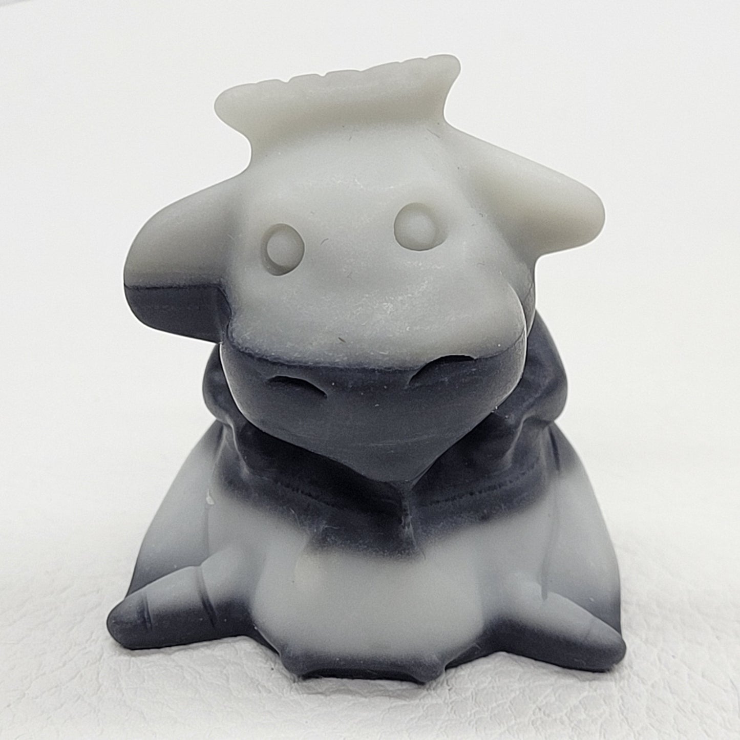 Tai Chi cow carving in black, white, and gray colors placed on a white surface.