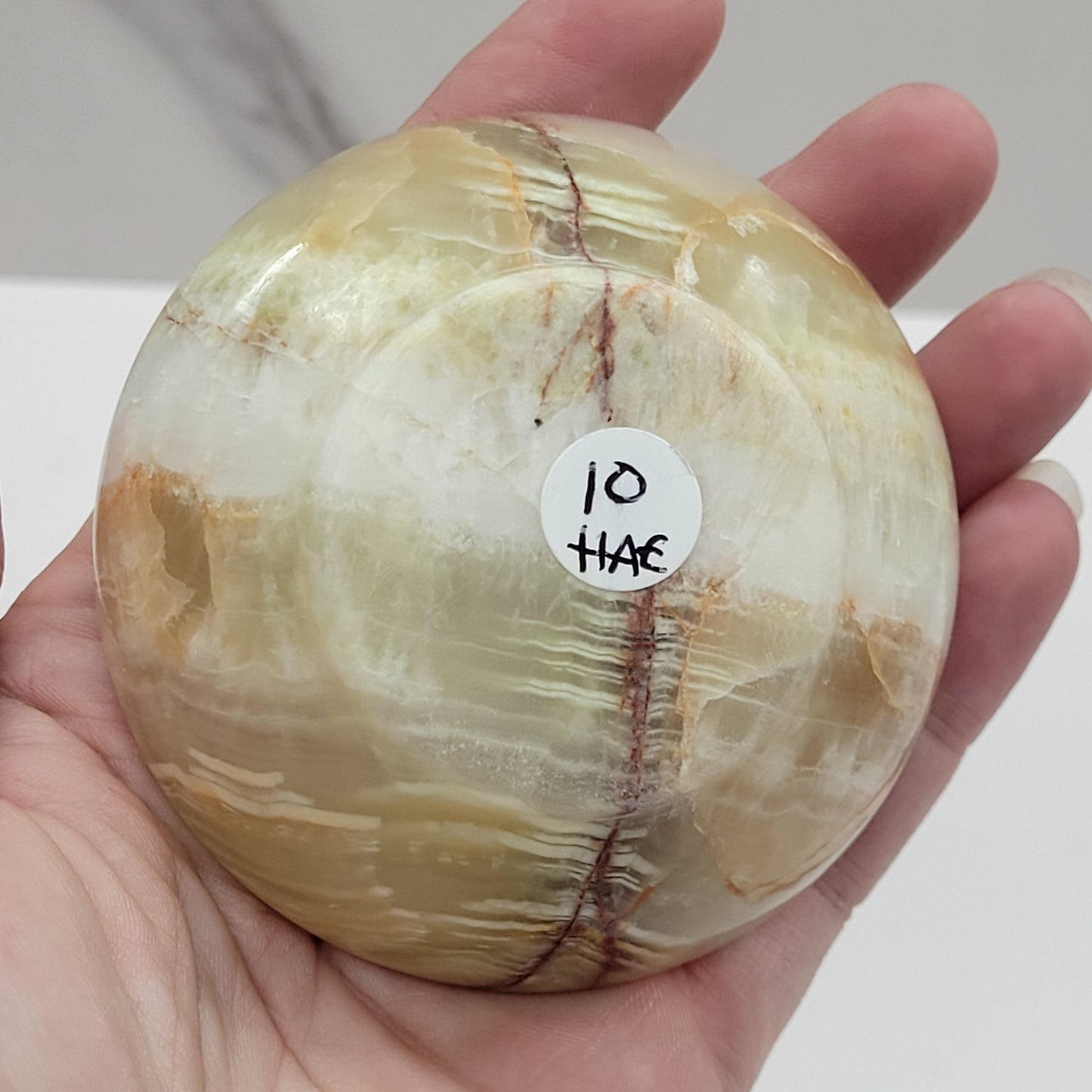 Hand holding an onyx bowls with marbled patterns on a white surface