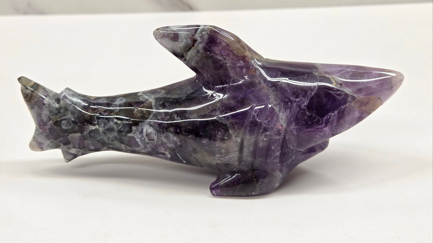 Carved Dream Amethyst shark figurine on a white background