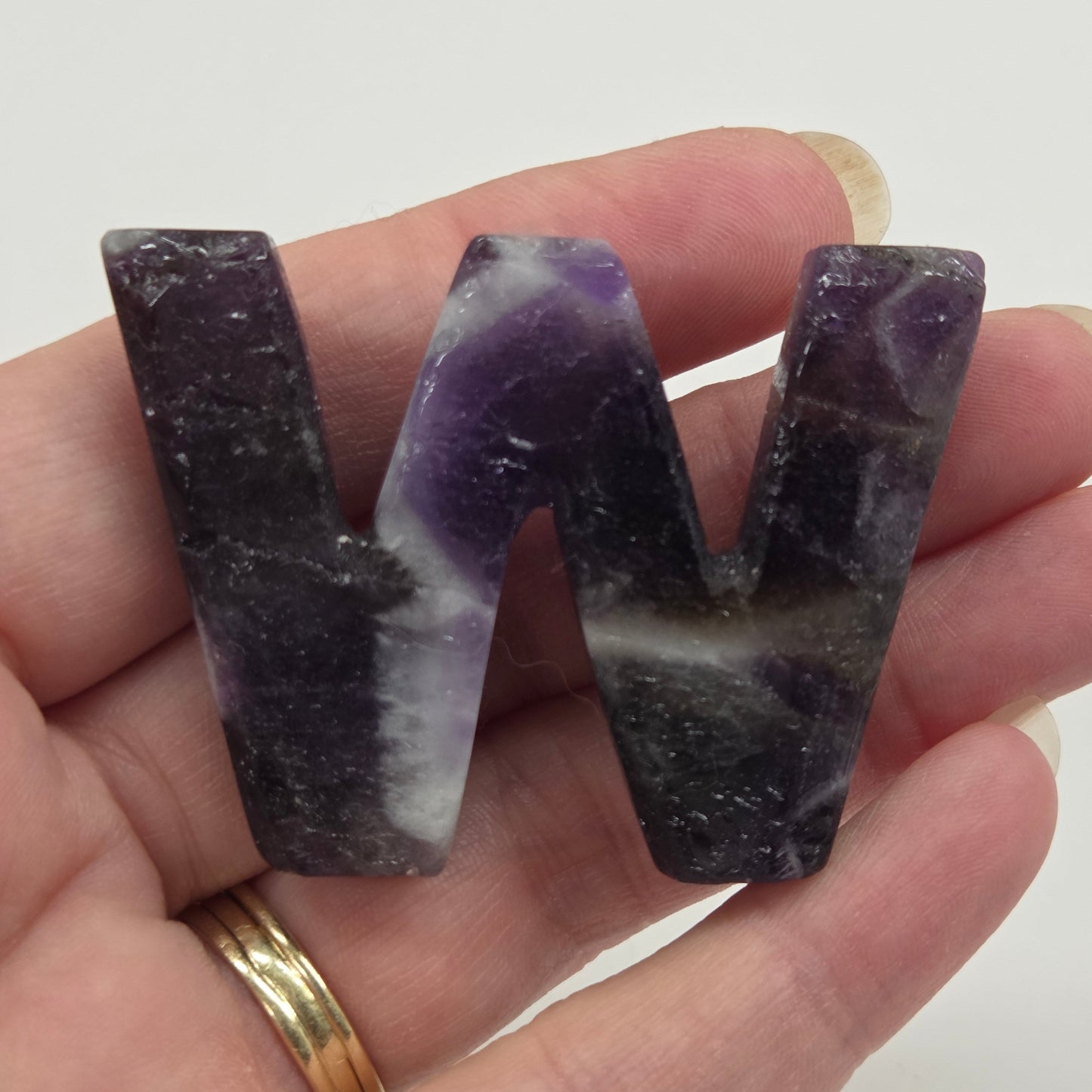 Dream Amethyst carved letter 'W' being held in a hand