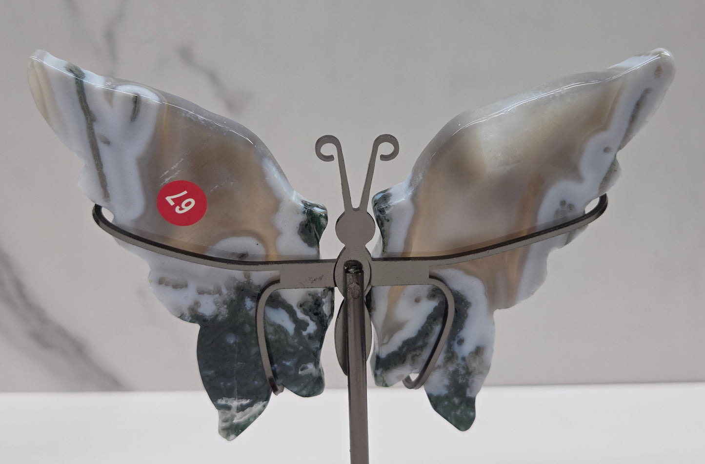 Moss Agate crystal carved butterfly wing decorations on a stand.