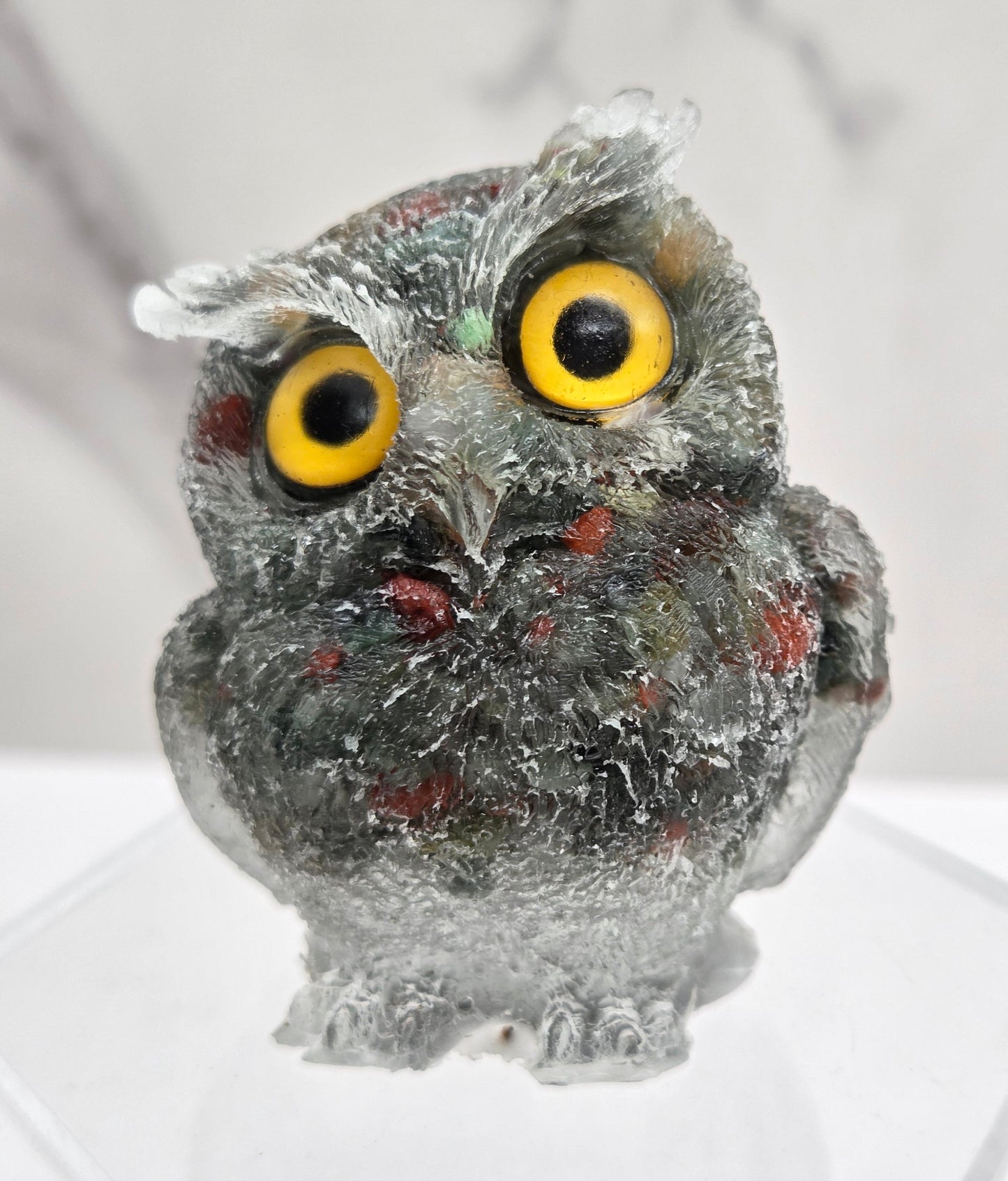 A resin owl figurines with various colorful crystal chips embedded within, displayed on a white background.