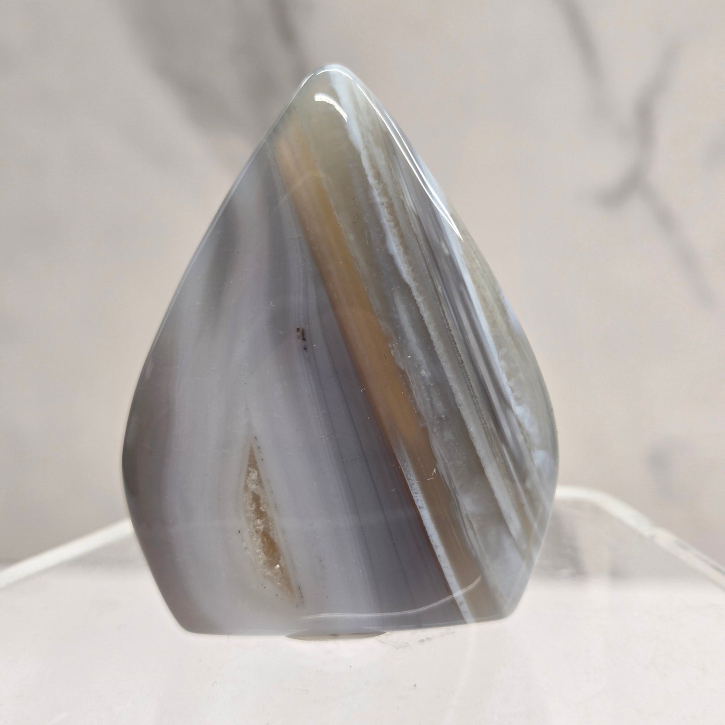 A teardrop-shaped agate stone on a light gray background