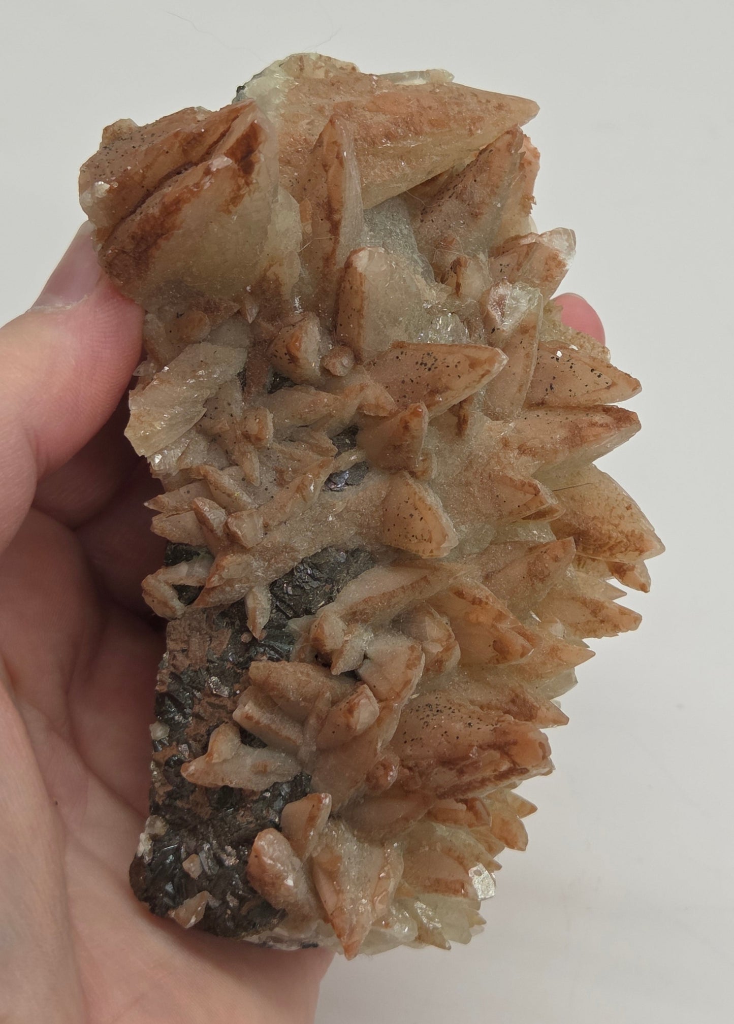 Hand holding a crystal formation against a plain background