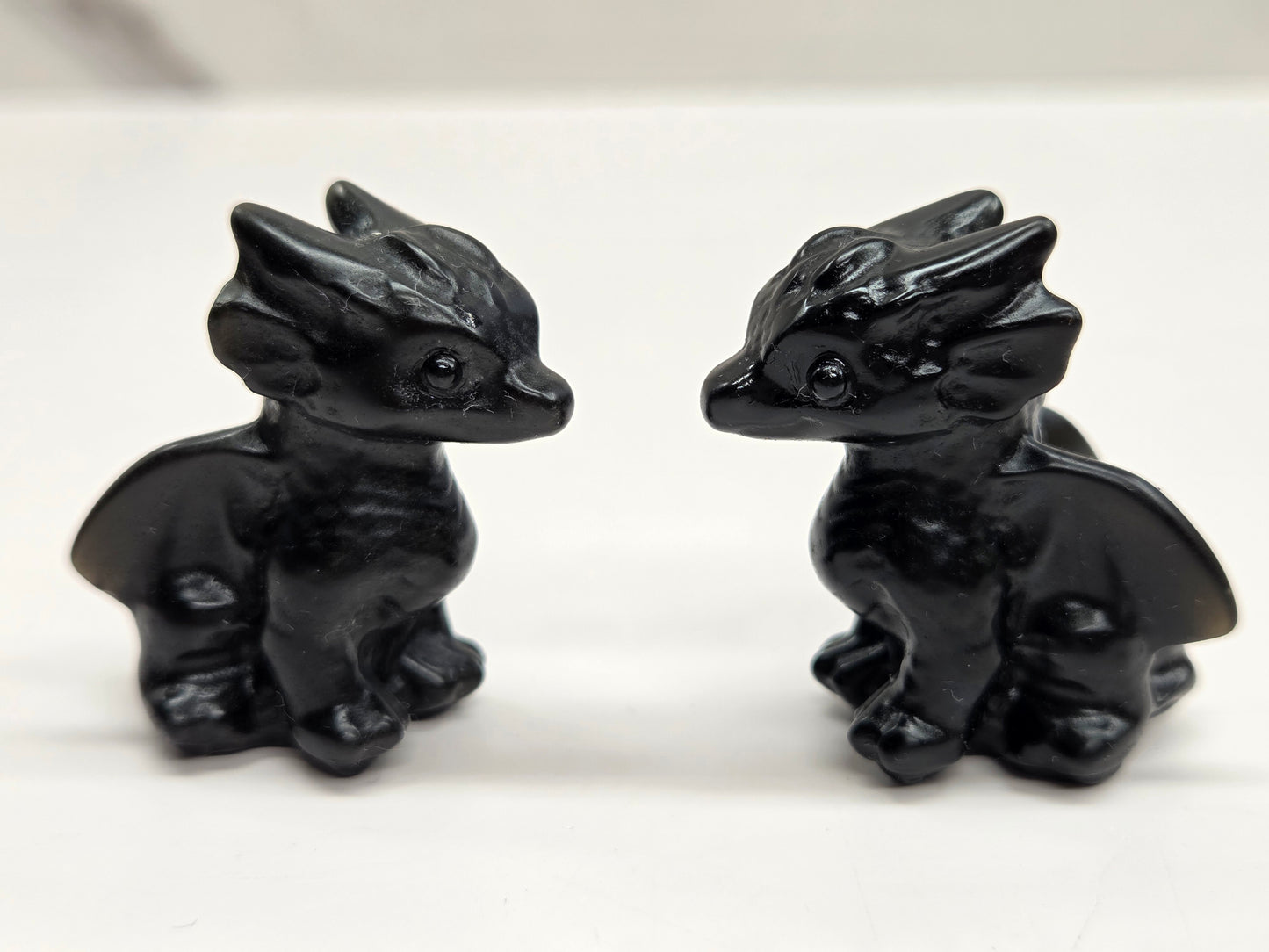 Two Small, crystal carvings resembling dragons a neutral background