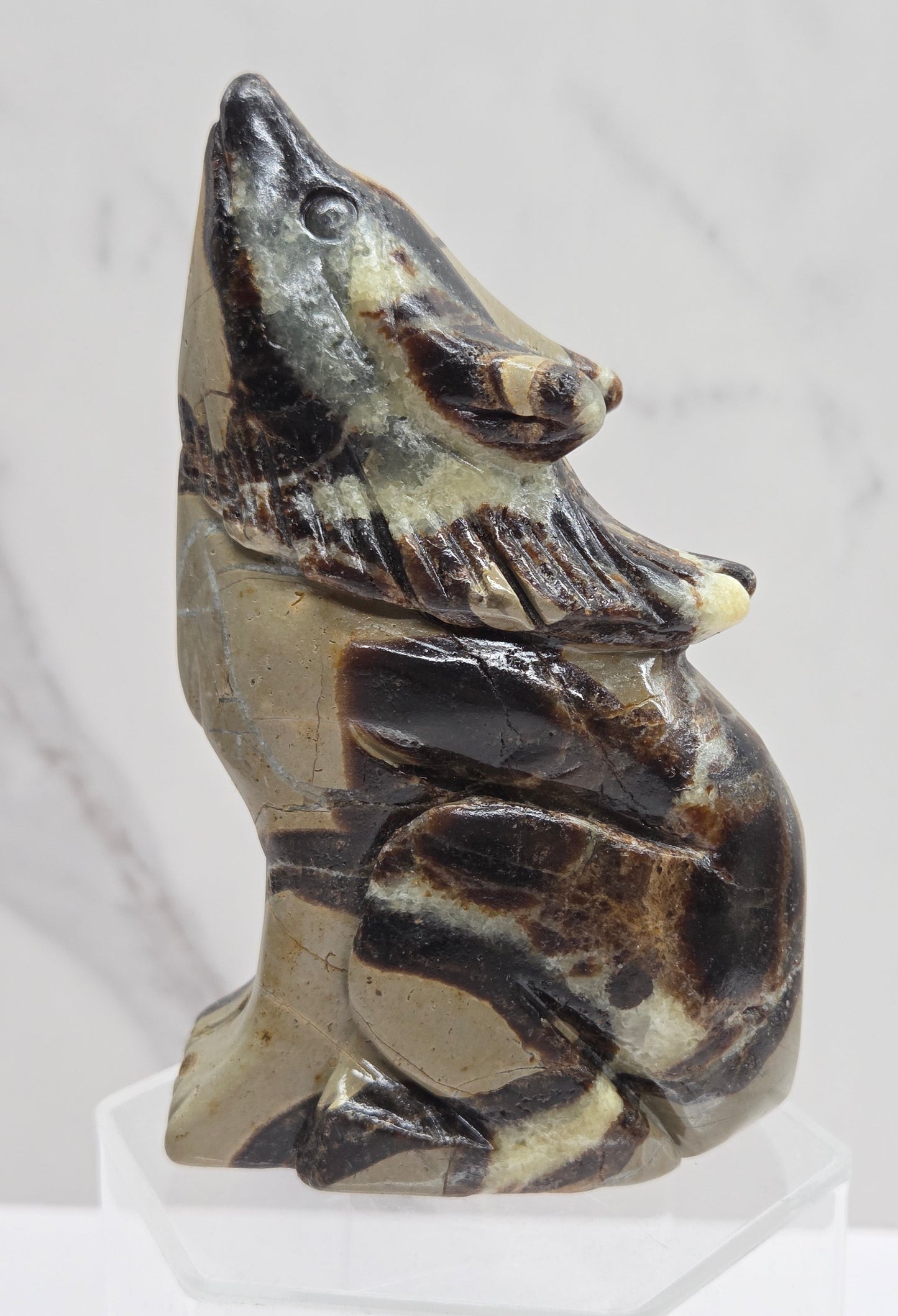 Septarian wolf carving with yellow, tan and brown coloring on a white background