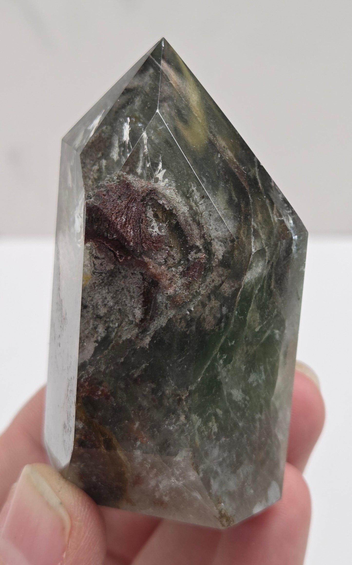 Hand holding a Garden Quartz crystal against a white background