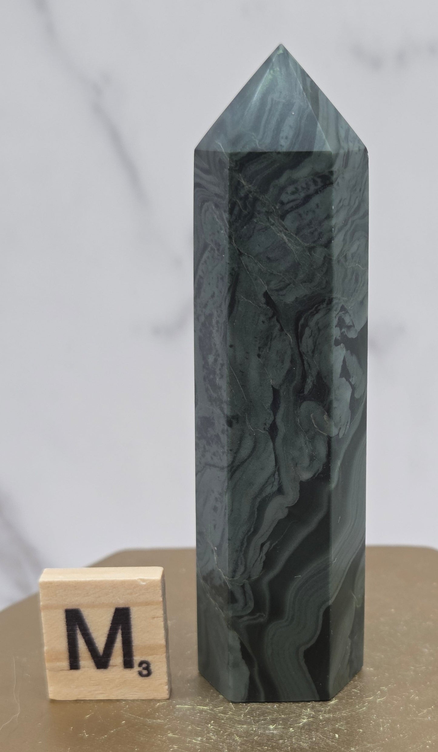 Green wave picture jasper tower on a wood base on a white background