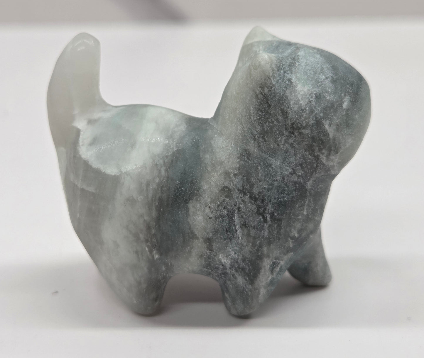 Small stone blue calcite sculpture of a cat on a white background