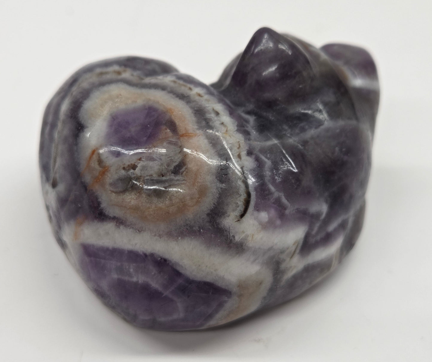 Dream Amethyst sleeping cat carving with banding on a white background