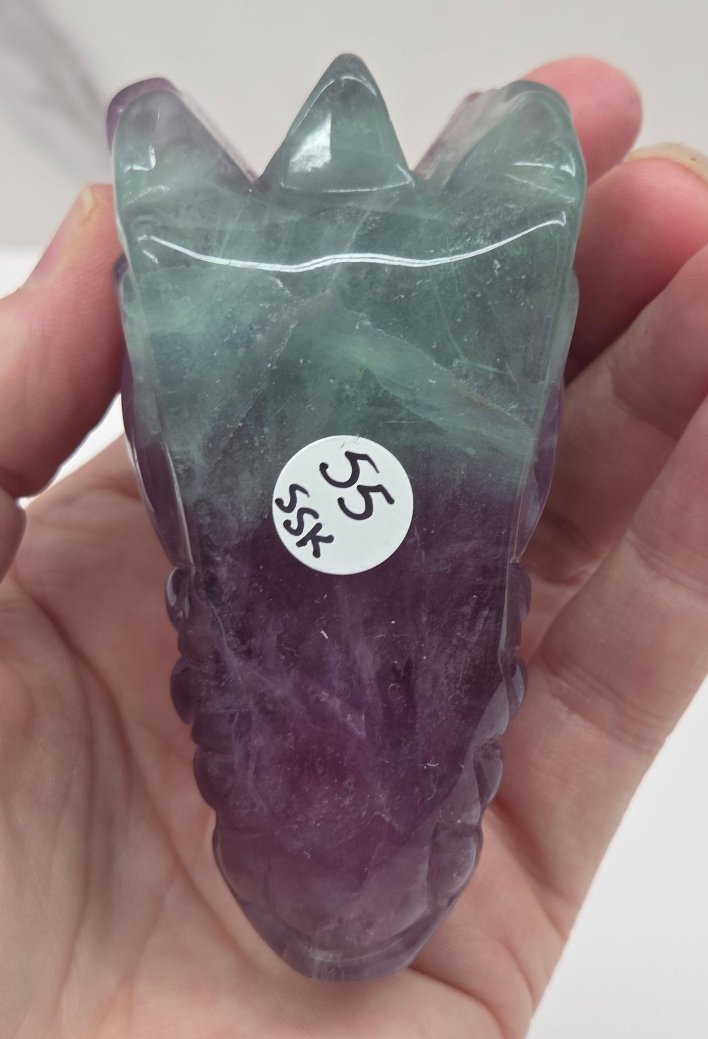 Underside of fluorite dragon head sculpture on a white surface