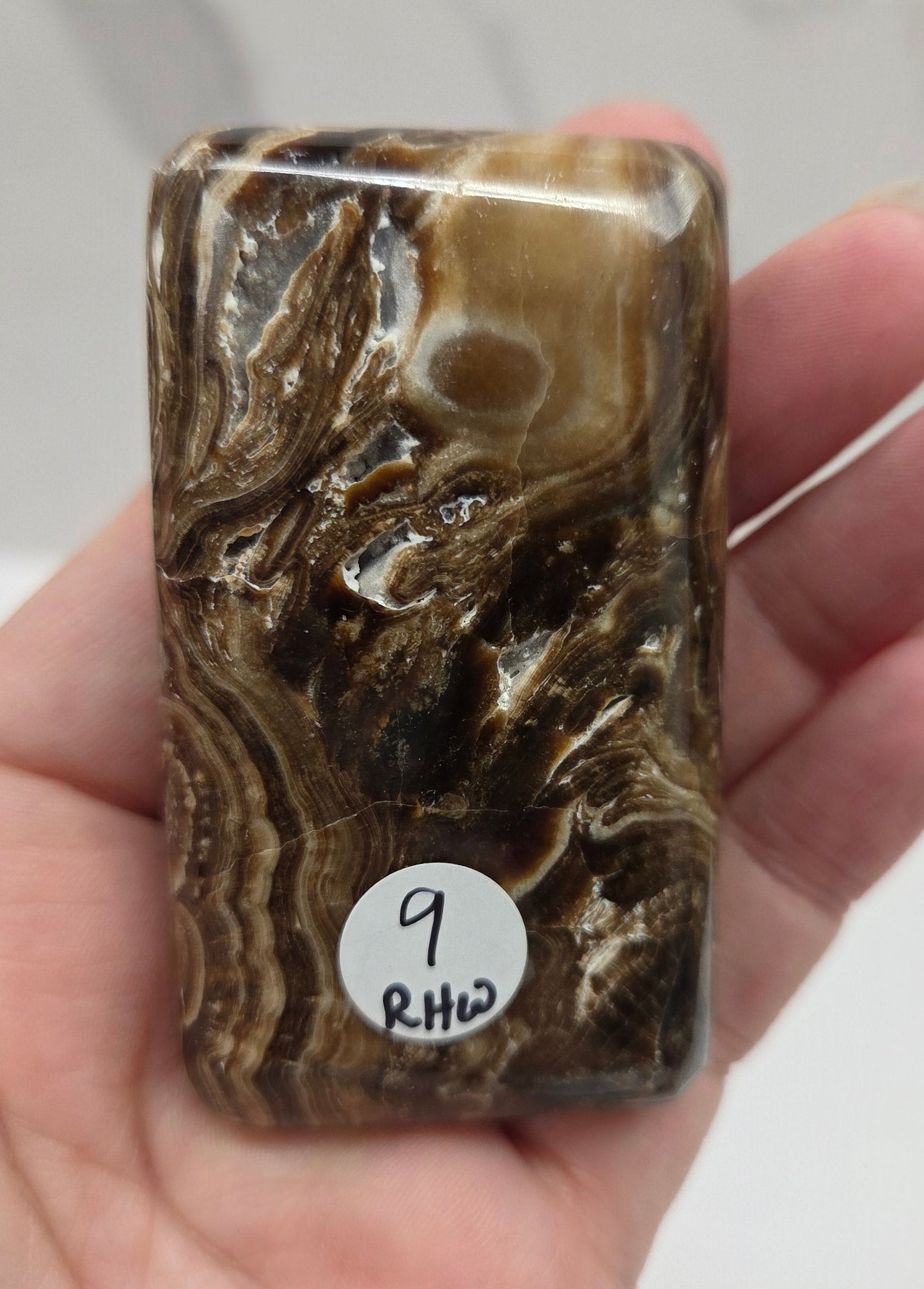 Hand holding a marbled stone with a label on a white background