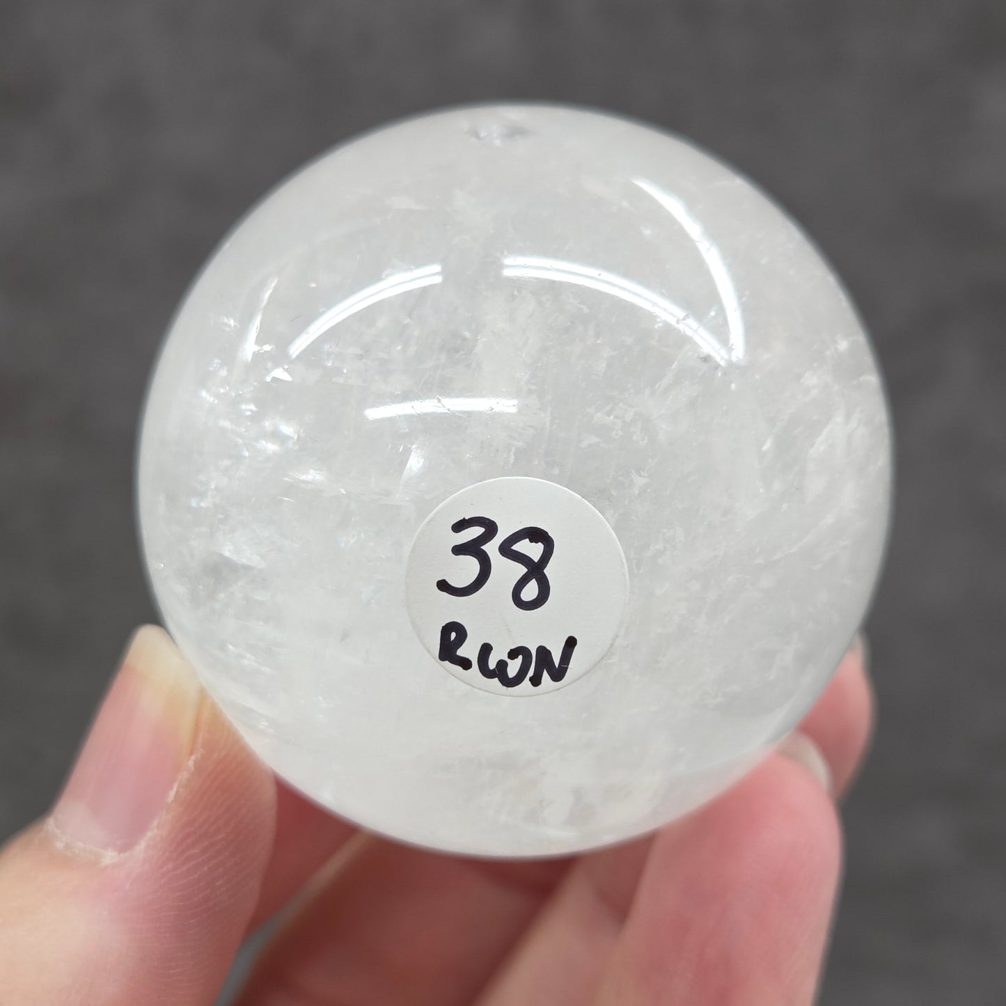 Clear crystal ball with a label held by a hand against a dark background