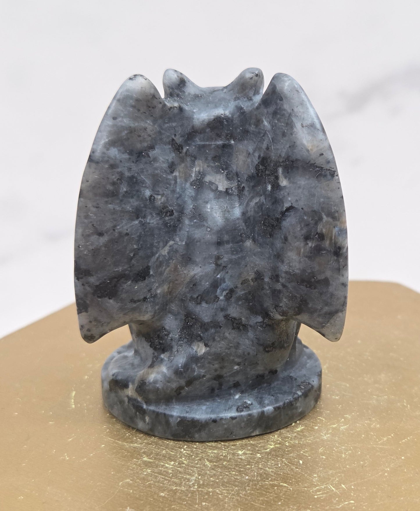 Decorative Larvikite gargoyle carving on a wooden surface with a white background
