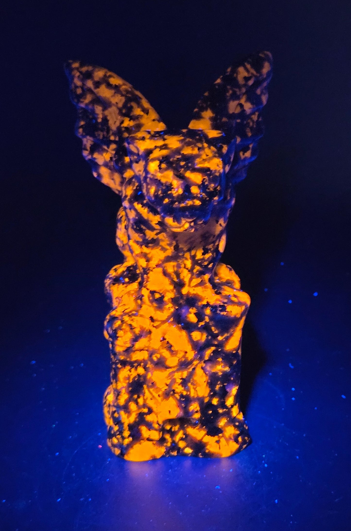 Yooperlite gargoyle carving on a dark carving under UV light