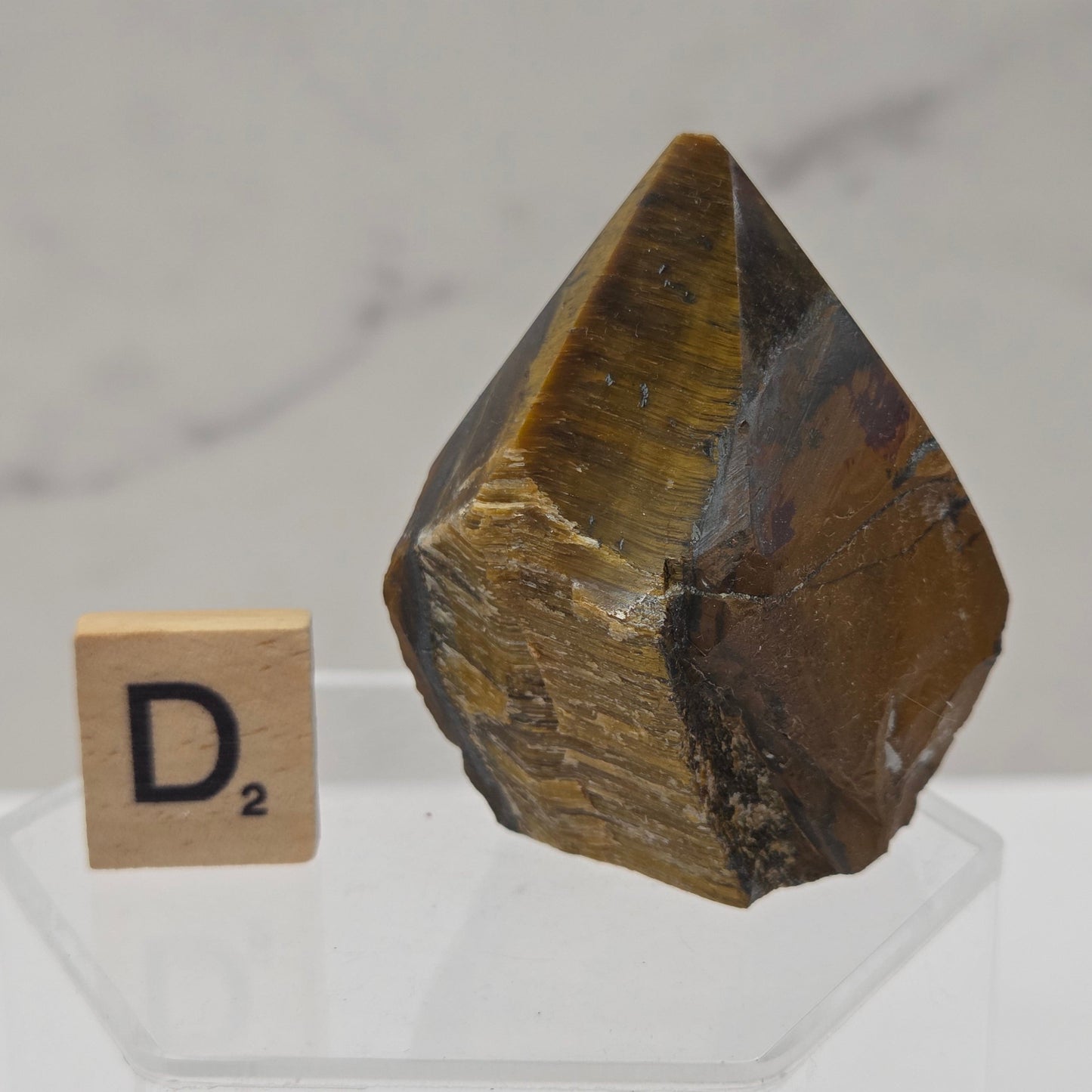Tigers Eye specimen on a white background with a small wooden block displaying 'A'