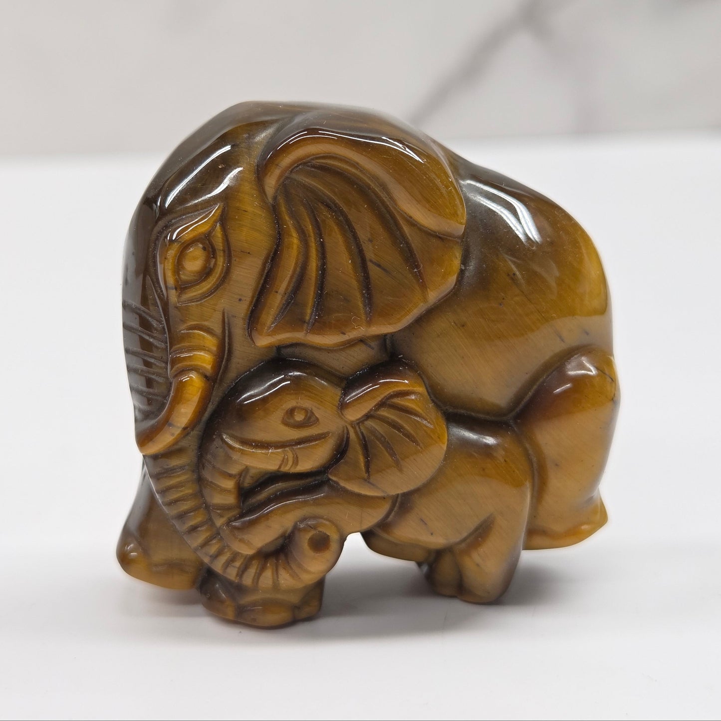 Tigers Eye elephant with baby carving on a neutral background