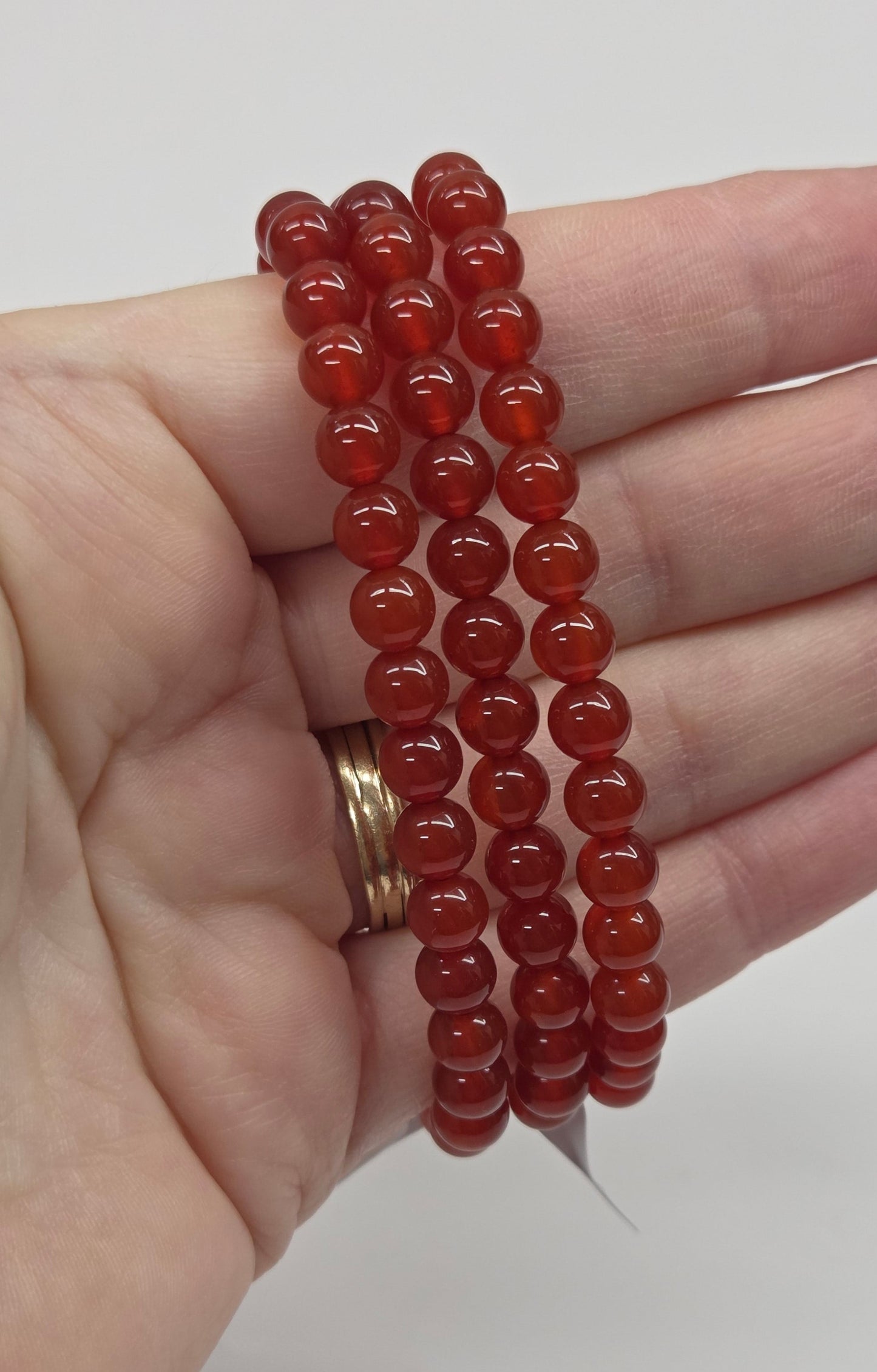 Hand holding a stack of red beaded bracelets against a white background