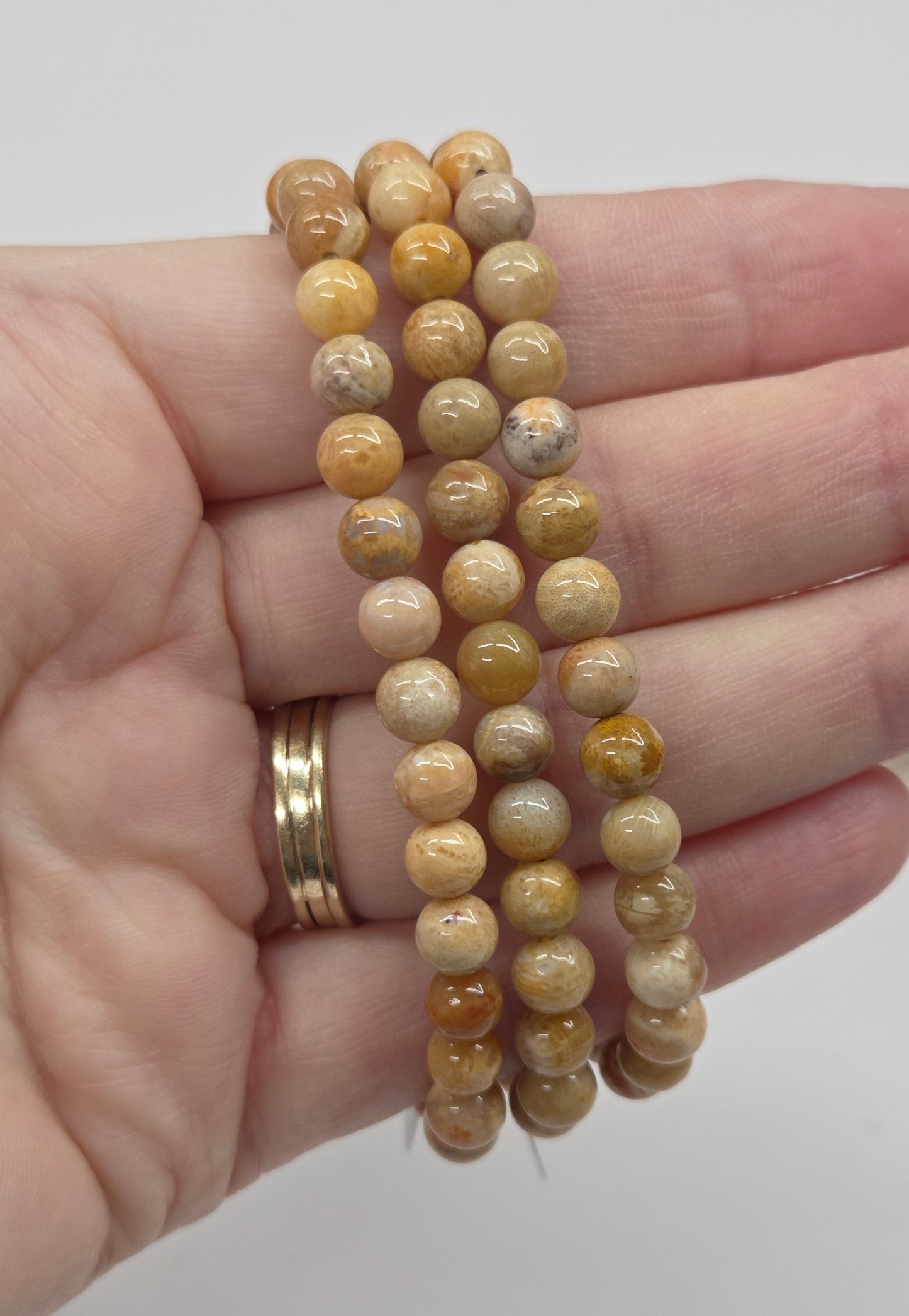 Hand wearing three beaded bracelets on a plain background