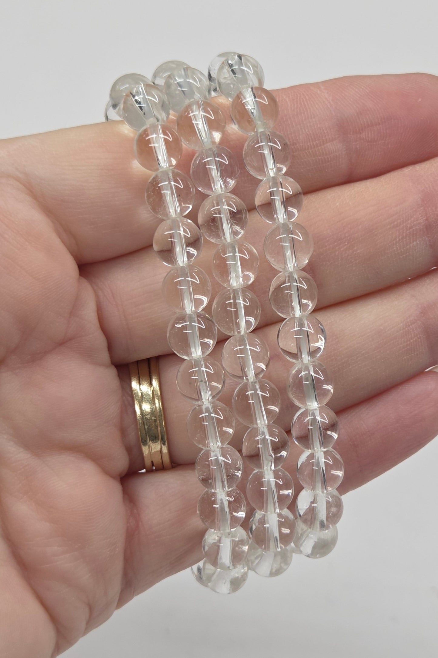 Clear beaded bracelets on a hand with a plain background