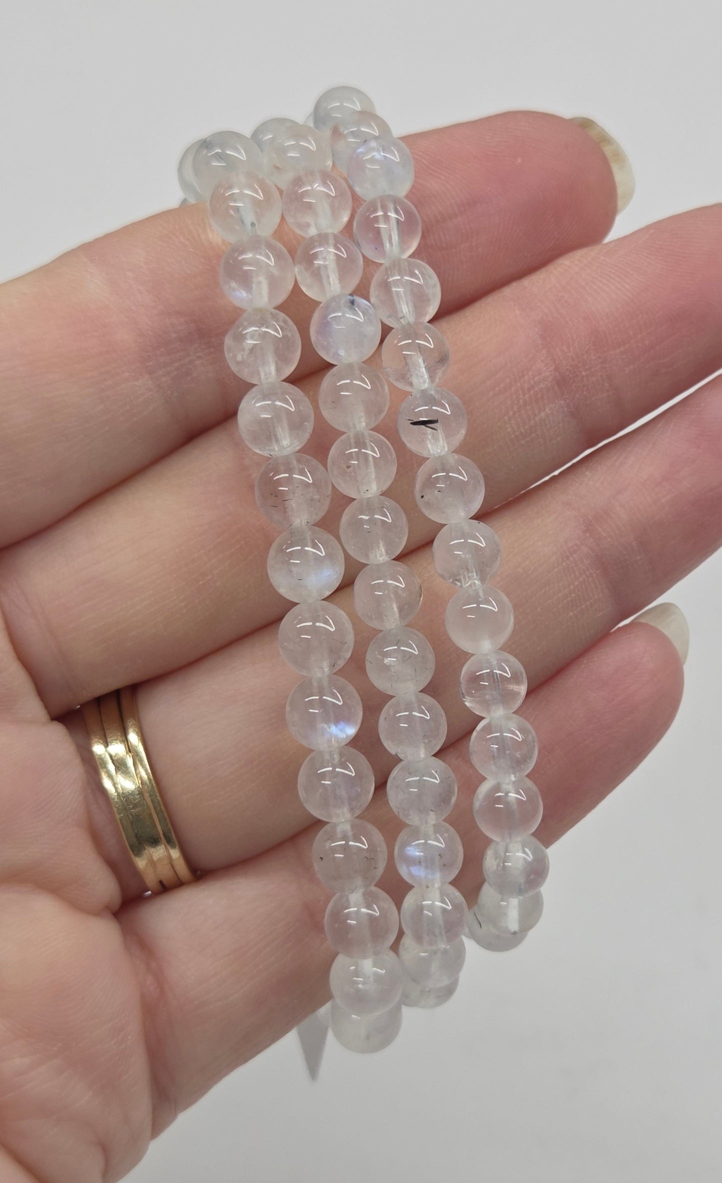 Hand holding clear beaded bracelets against a plain background