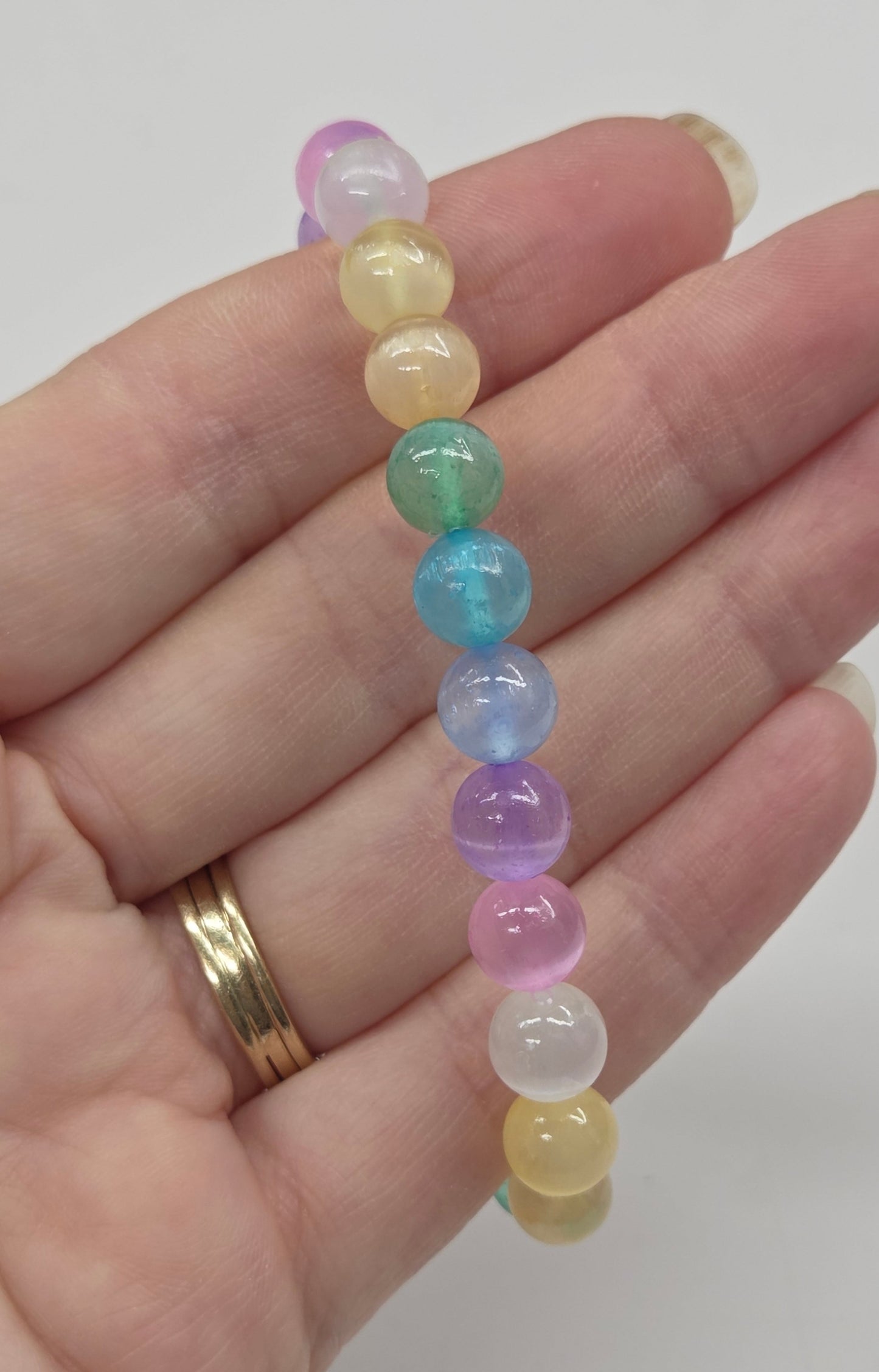 Colorful beaded bracelet on a hand with a plain background