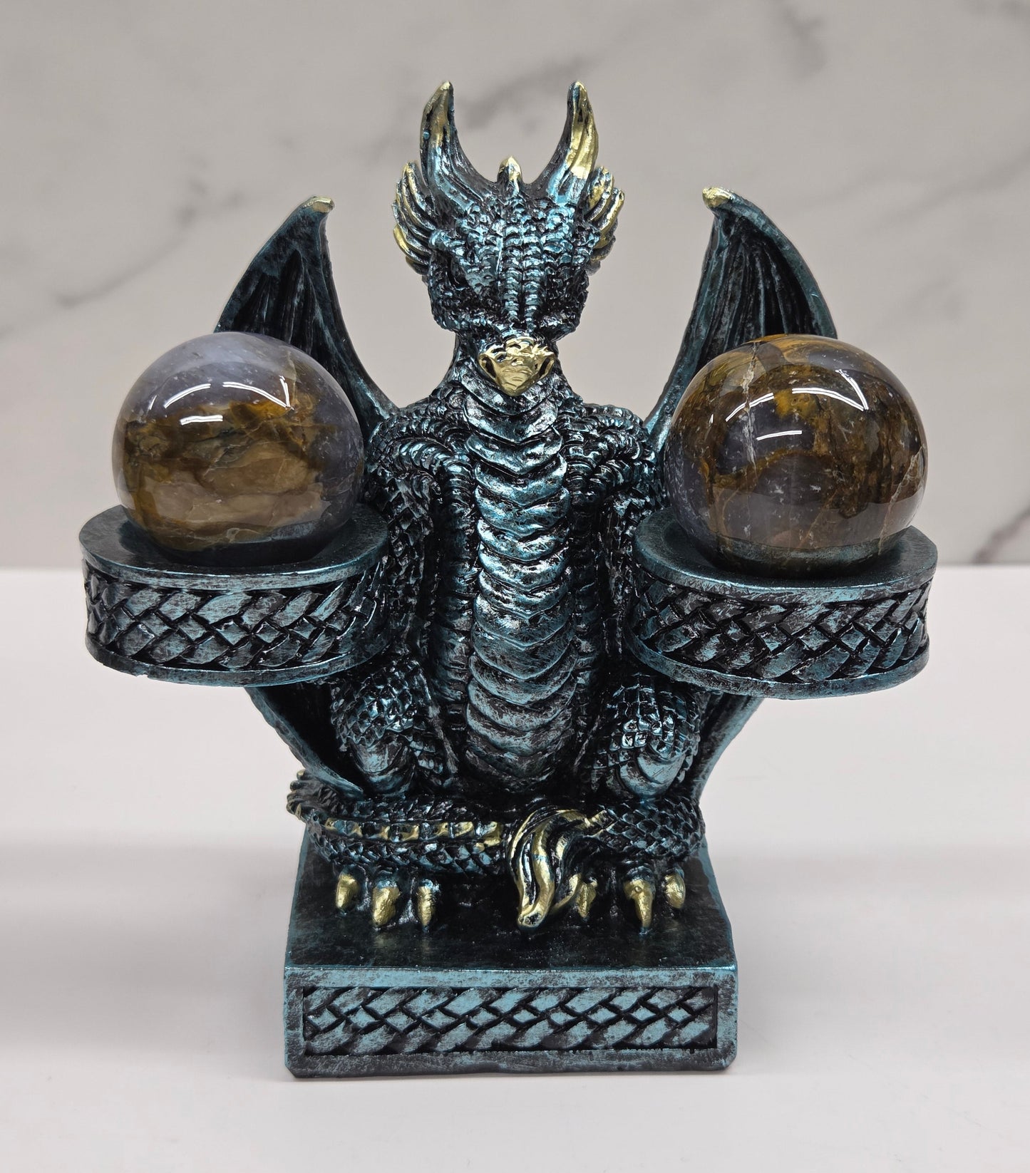 Decorative dragon-shaped sphere holder with 2 small spheres on a marble surface