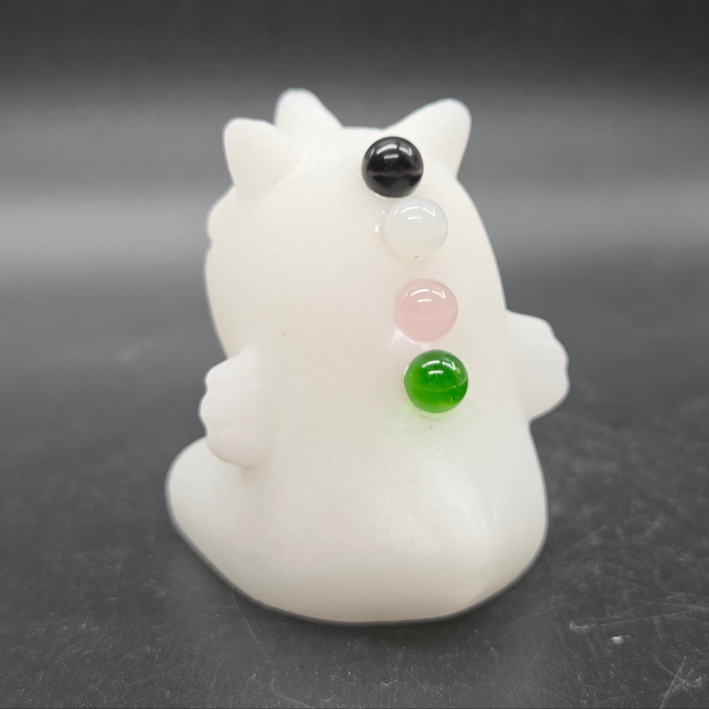 White unicorn-shaped figurine with colored beads on a dark background