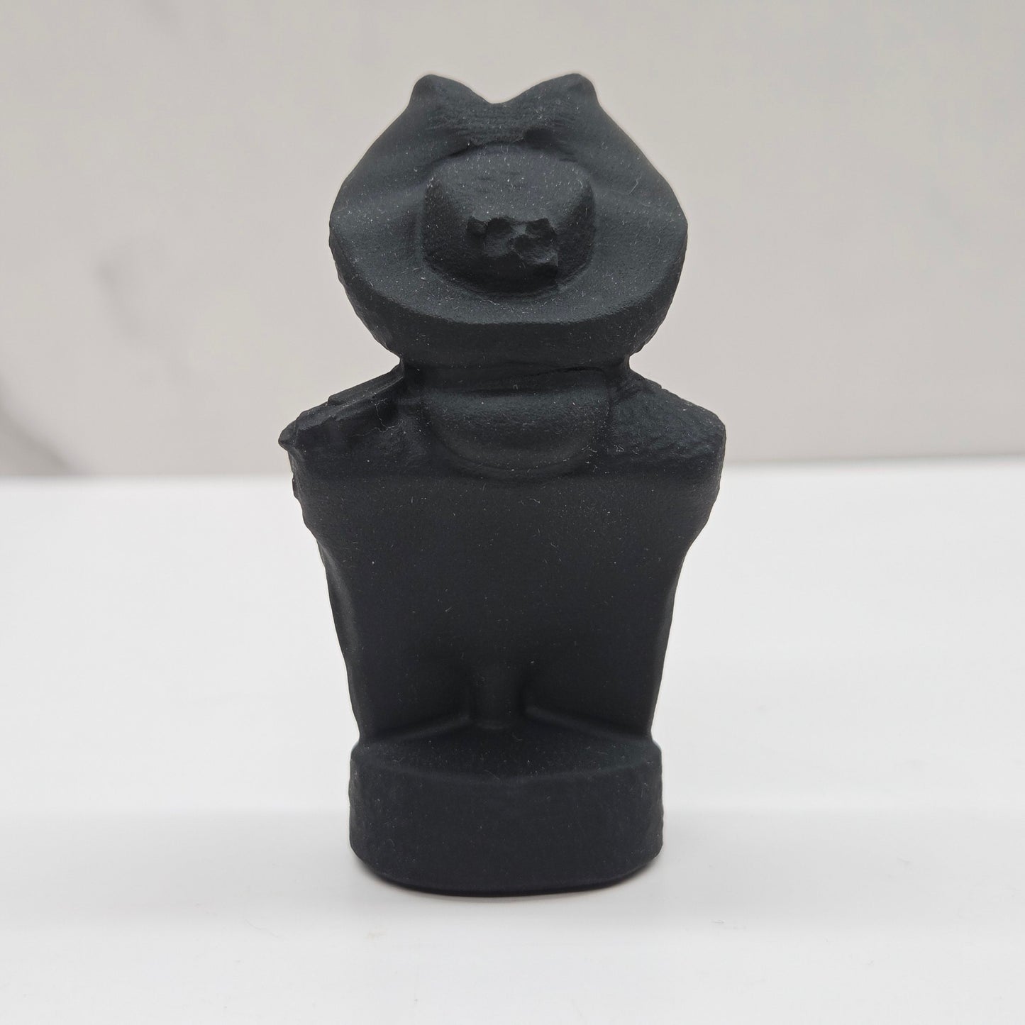 Black bust sculpture of a figure with a pirate hat on a white background