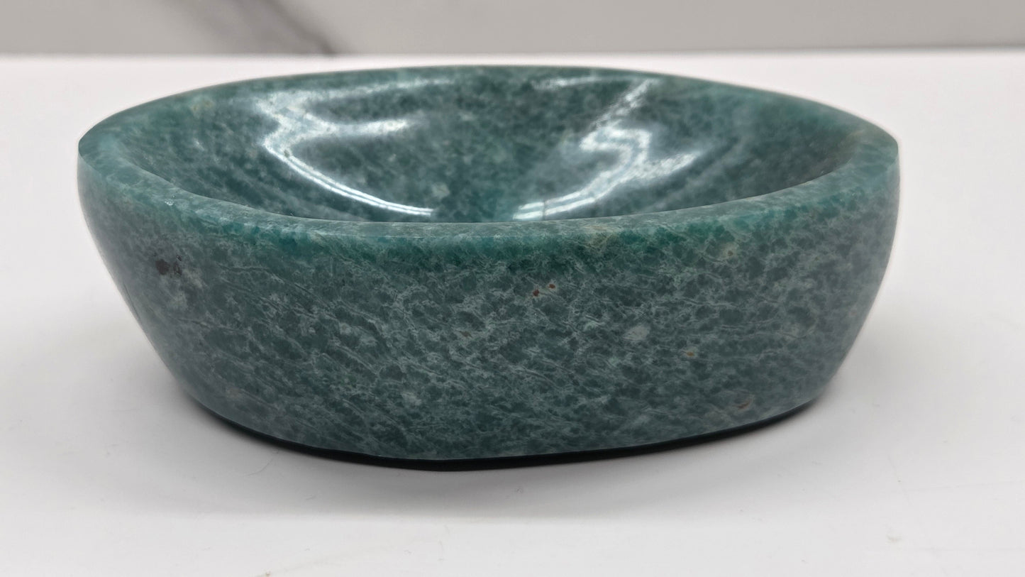 Green amazonite bowl on a white surface with a gray background
