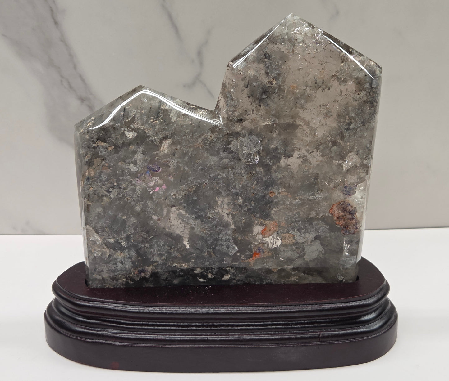 Decorative stone sculpture on a wooden base against a marble wall.