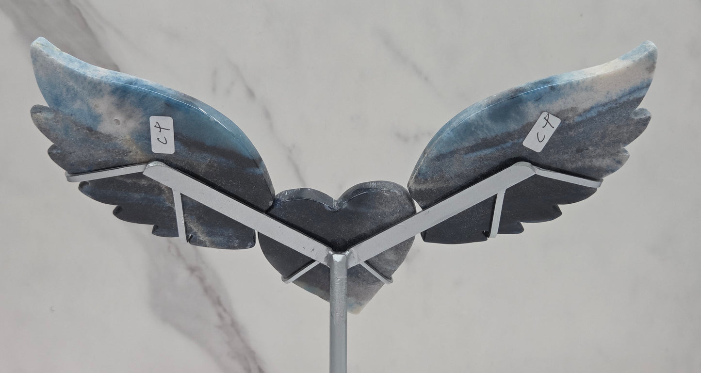 wing and heart carving with black, blue and white coloring on a silver stand against a white background