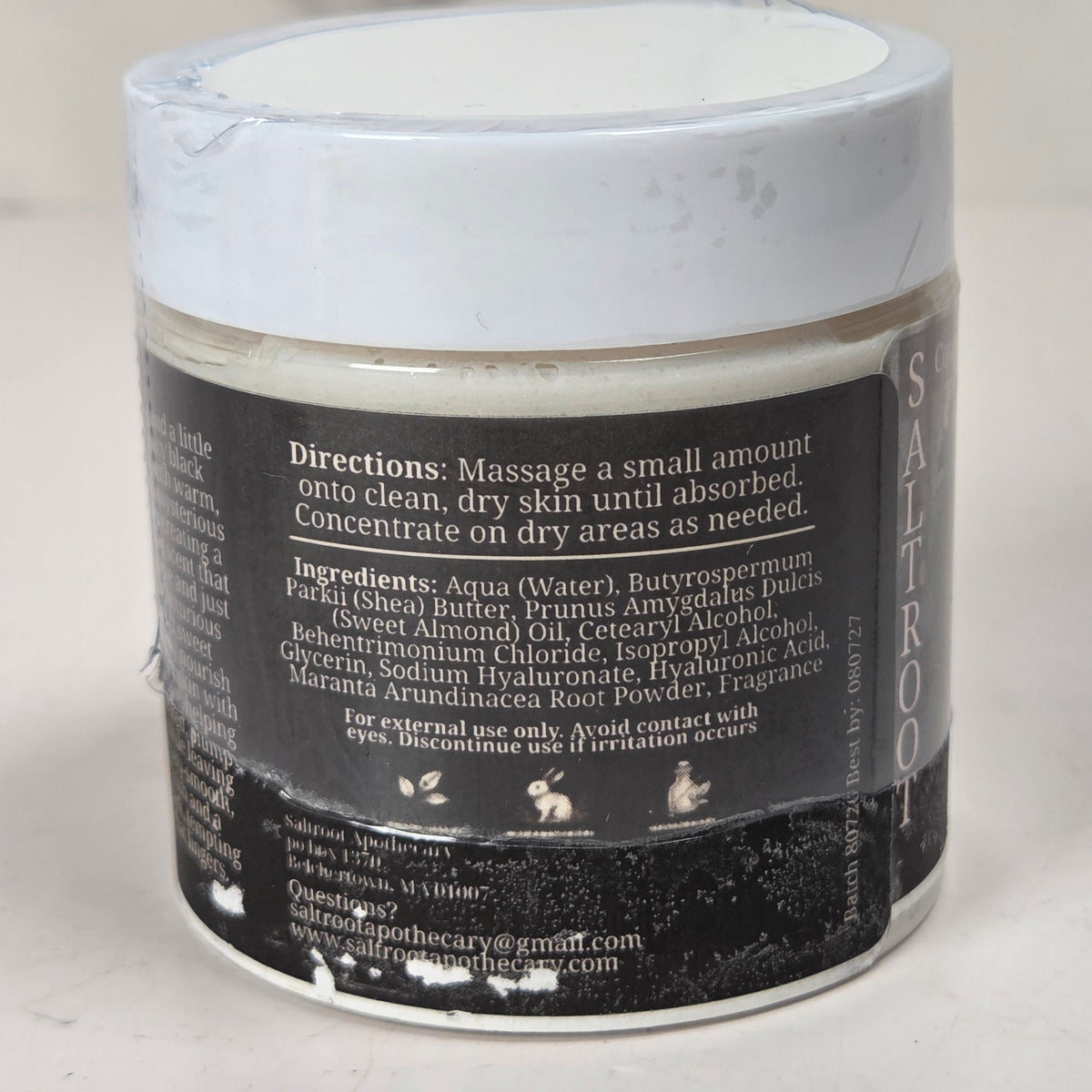 A jar of facial cleansing foam with a white lid, showing the back of the label with product details, set against a neutral light gray background.