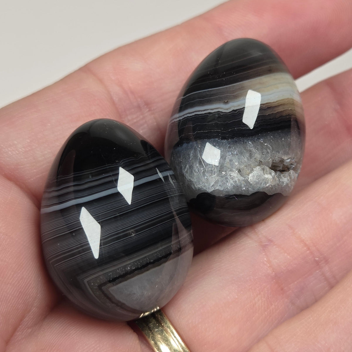 Person holding black and white agate egg shaped stones
