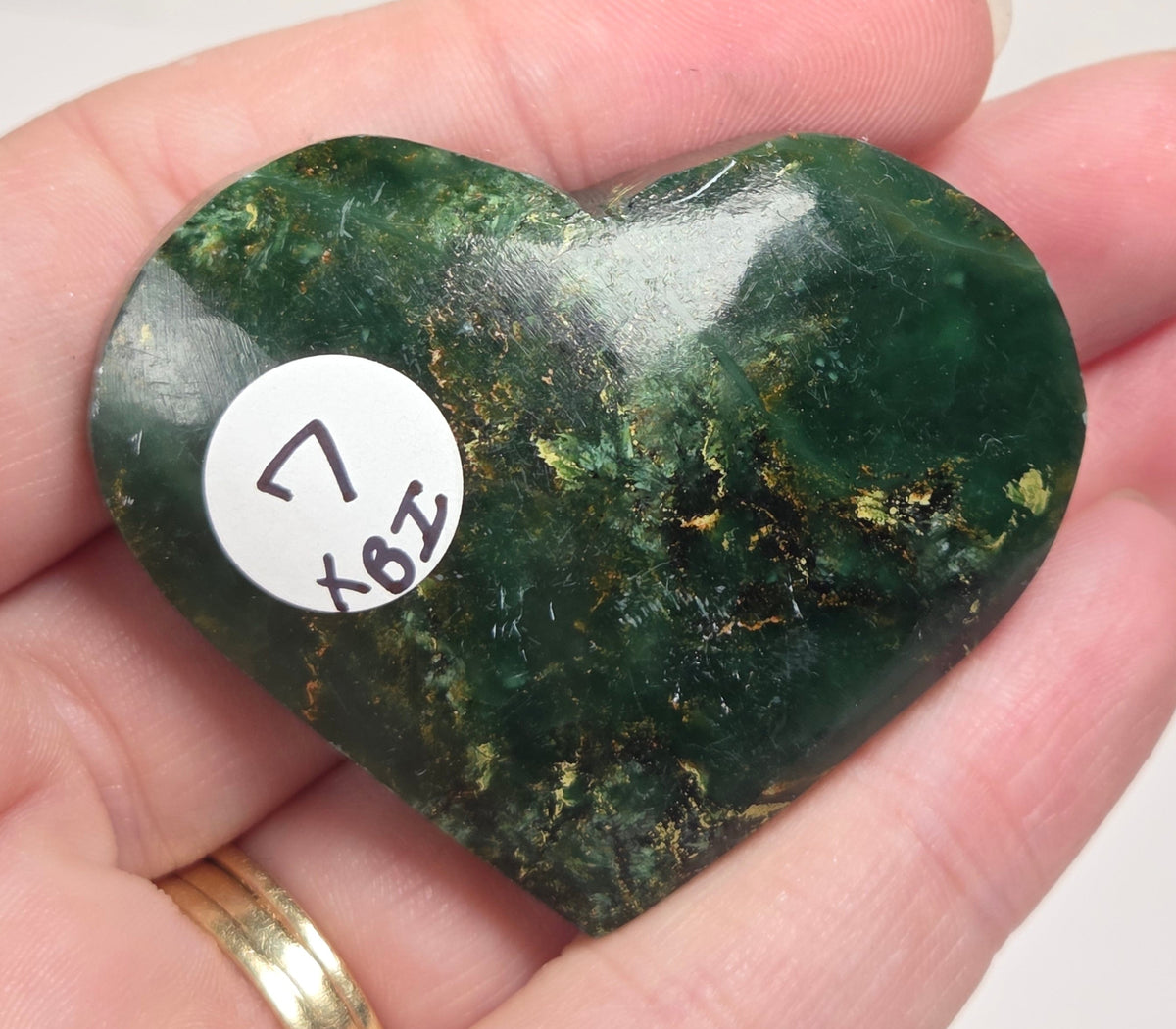 Heart-shaped green stone being held in a hand