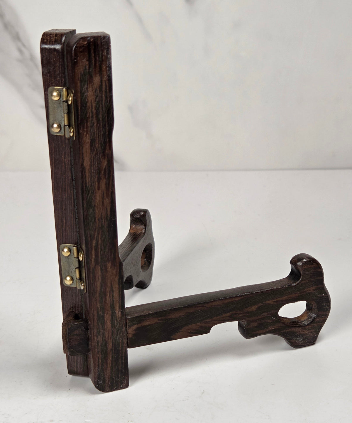 Dark wooden stand on a white surface with a marble-patterned wall in the background