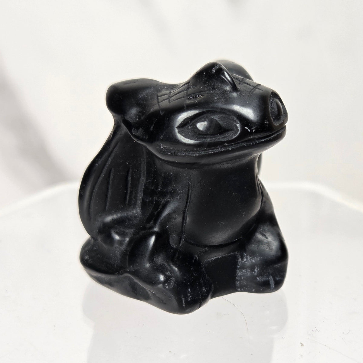 Obsidian toothless carving on an acrylic stand against a white background