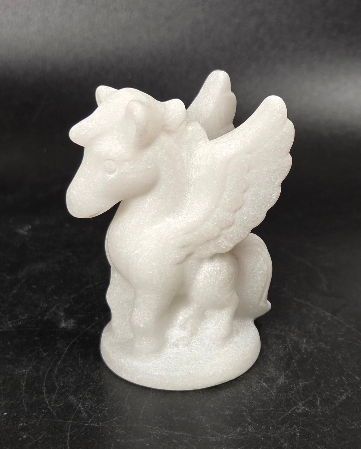 Stone sculpture of a winged creature on a black background