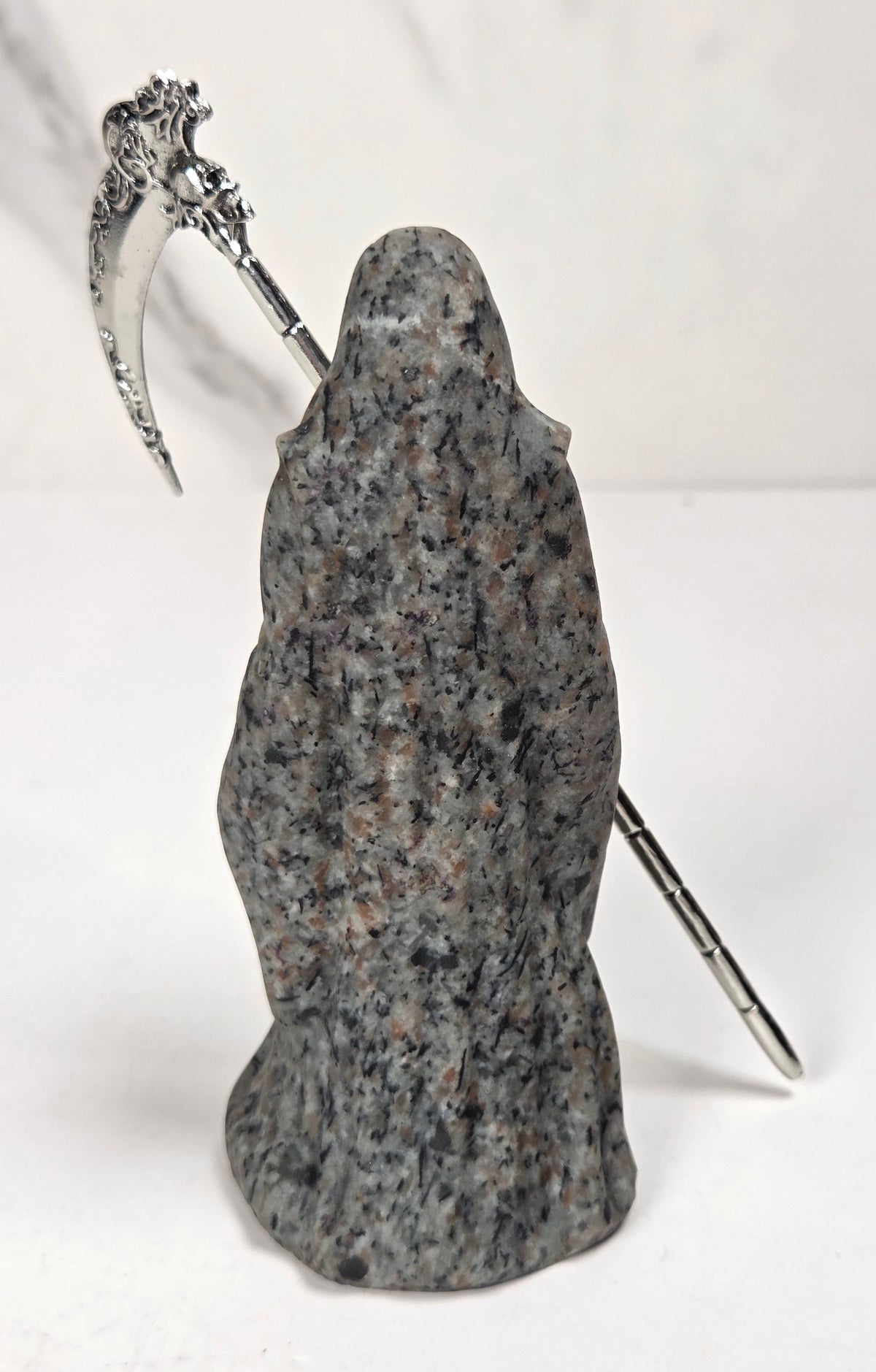 Reaper style crystal carving with black and grey coloring with a metal scythe against a marbled background