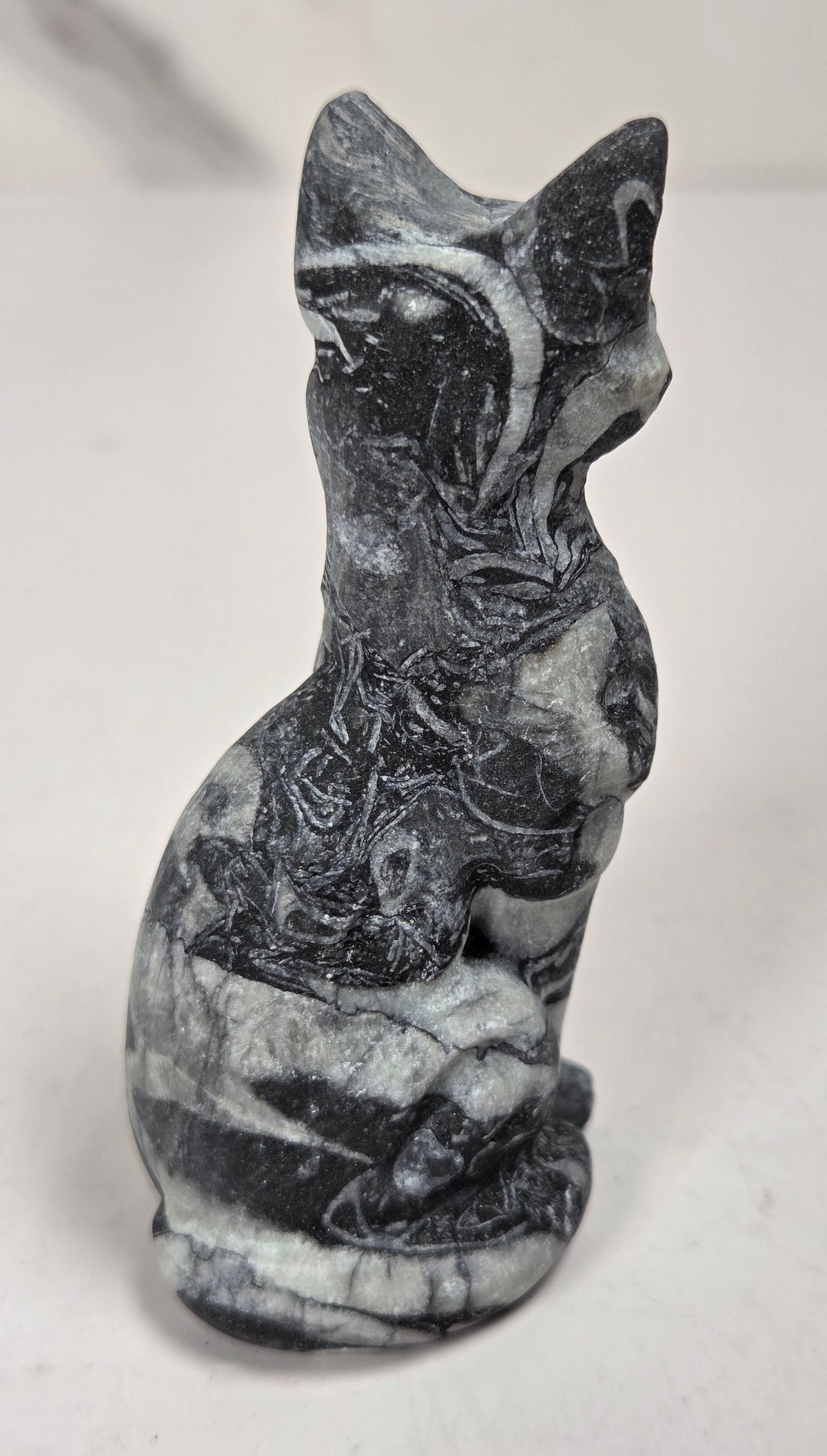 Black and white banded crystal cat shaped carving with scroll work against a white background