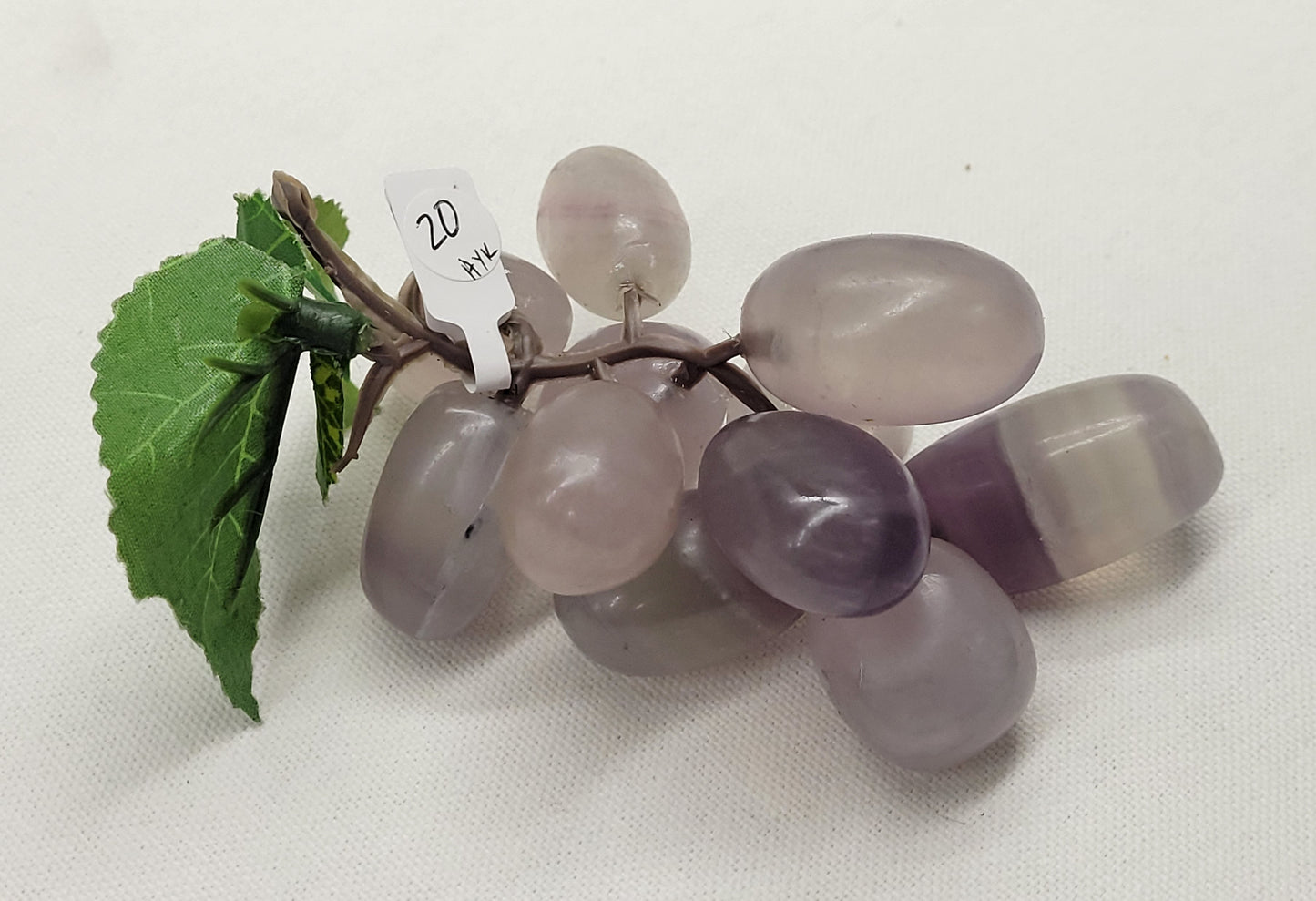 Purple Fluorite grape cluster carving on a white background