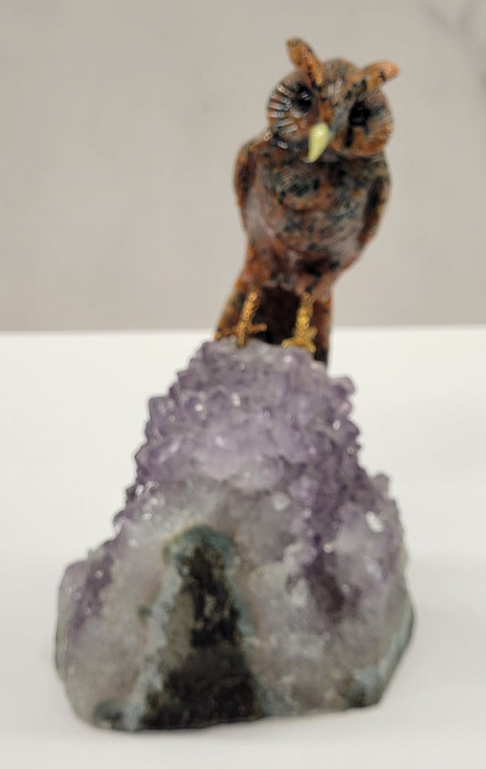 A collection of bird carvings on amethyst cut bases, featuring an owl, displayed against a neutral background.
