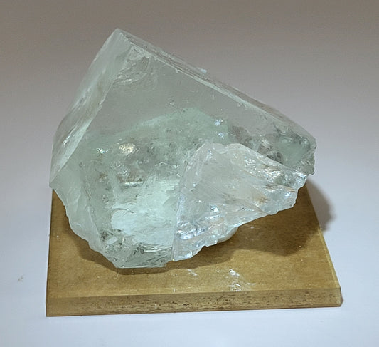 Green Fluorite crystal on a wooden platform with a plain background.