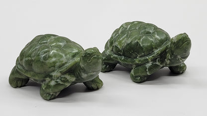 Two green jade turtle figurines against a white background.