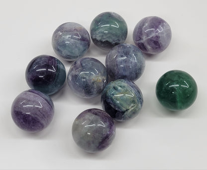 A collection of small, multicolored fluorite spheres on a white background.