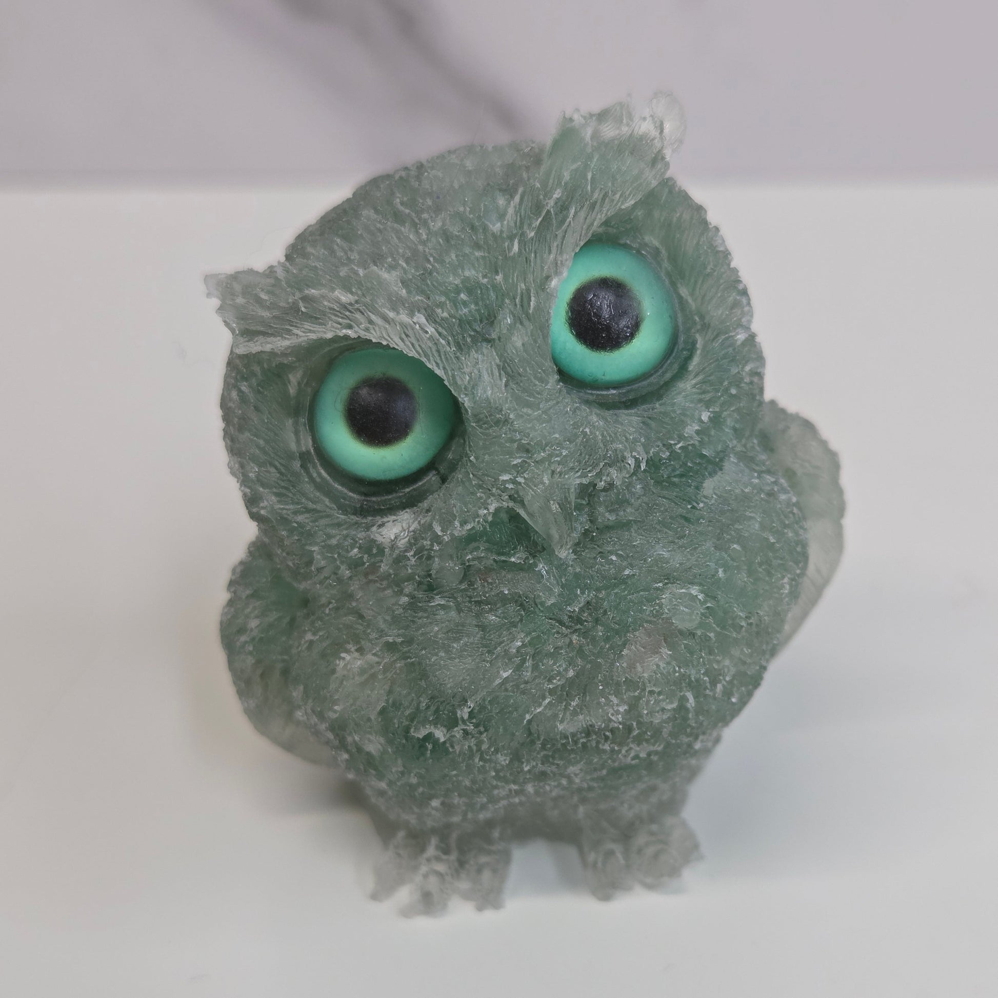 A resin owl figurines with various colorful crystal chips embedded within, displayed on a white background.