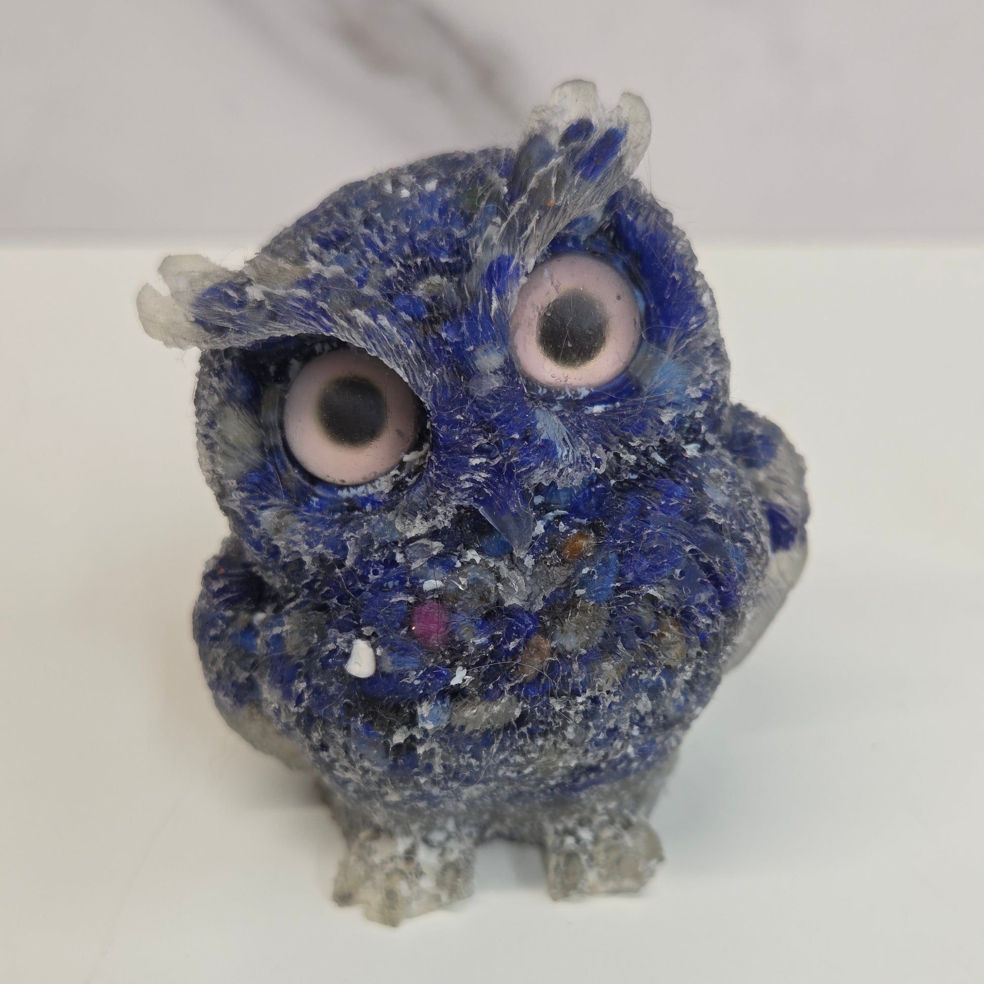 A resin owl figurines with various colorful crystal chips embedded within, displayed on a white background.